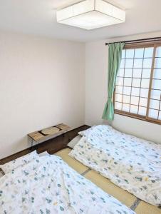 1 dormitorio con 2 camas y ventana en 1棟貸 白老 登別 癒やしの宿 源泉掛け流し温泉 hokkaido noboribetsu shiraoi en Shikyū
