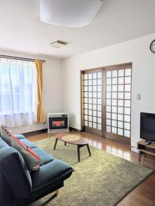 a living room with a blue couch and a tv at 1棟貸 白老 登別 癒やしの宿 源泉掛け流し温泉 hokkaido noboribetsu shiraoi in Shikyū