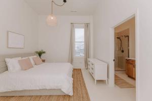 a white bedroom with a white bed and a window at East Main Lofts - Roller Rink 301 in Madison