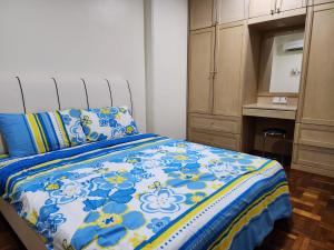 a bedroom with a bed with a blue and white comforter at Riverbank Suites Kuching Waterfront in Kuching