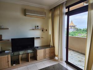 een woonkamer met een flatscreen-tv naast een raam bij Riverbank Suites Kuching Waterfront in Kuching