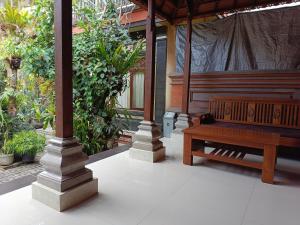 un banco de madera sentado bajo un pabellón con plantas en Nyoman House Ubud, en Ubud