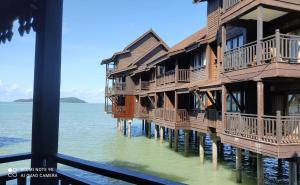 a row of wooden buildings on the water at Villa Dalam Laut 580 in Pantai Cenang