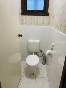 a white bathroom with a toilet and a window at 6677 in Glen Waverley