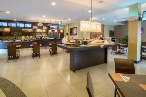 un restaurante con barra de desayuno, mesas y sillas en Courtyard by Marriott San Jose Airport Alajuela, en Alajuela