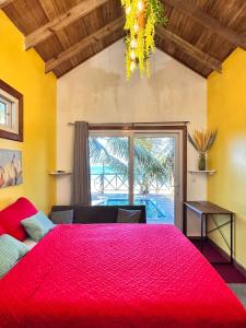 a bedroom with a large red bed and a window at Villa Devonia - Beachfront Cabins with Pool at Tela, HN in Tela