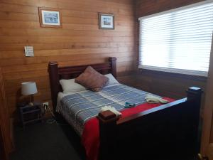 een slaapkamer met een bed in een kamer met houten wanden bij Three Bedroom Escape with Room to Roam in Rocky Cape