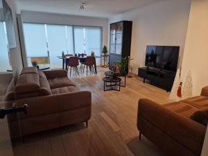 un soggiorno con divano e TV di Gezellig appartement Beveren-Waas Donkvijver a Beveren