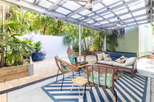 eine Terrasse mit einer Pergola, Stühlen und einem Sofa in der Unterkunft Tropical Garden Villa 5 mins from City Centre in Parap
