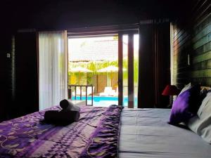 a bedroom with a bed with a view of a pool at Bunutbali Villas88 in Nusa Lembongan