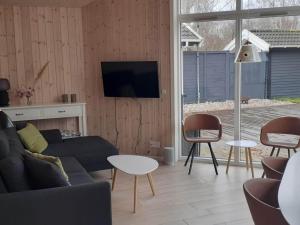 een woonkamer met een bank en een tv aan de muur bij Holiday home Jægerspris III in Jægerspris