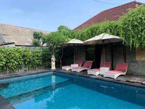 una piscina con tumbonas y sombrillas en Bunutbali Villas88, en Nusa Lembongan