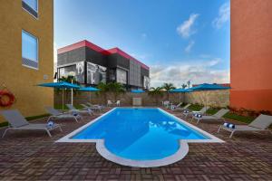 a swimming pool with chairs and a building at City Express Junior by Marriott Cancun in Cancún