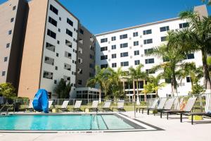 a pool with lounge chairs and palm trees in front of buildings at Element Miami Doral in Miami