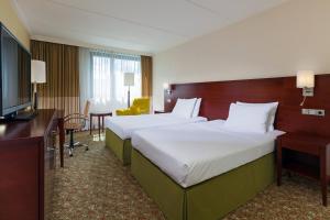 a hotel room with two beds and a television at Courtyard by Marriott Düsseldorf Seestern in Düsseldorf