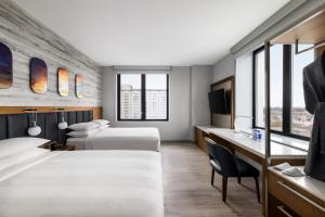 ein Hotelzimmer mit 2 Betten und einem Schreibtisch in der Unterkunft Marriott New York JFK Airport in Queens