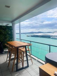 Una mesa y sillas en un balcón con vista al agua. en Luxury Apartment - Parking - Hot Tub - Stunning Views, en Auckland