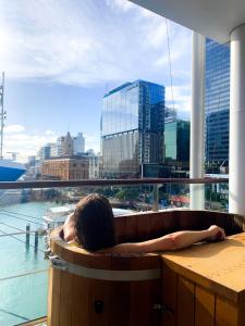 a woman sitting in a bath tub in a room with a view at Luxury Apartment - Parking - Hot Tub - Stunning Views in Auckland