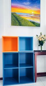 a blue and orange book shelf with a painting on the wall at Gem Villa 67, biệt thự 15 phòng có hồ bơi lớn in Ho Chi Minh City