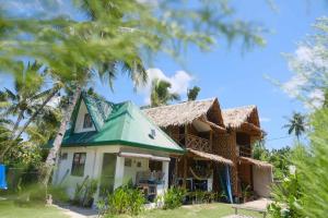 a house with a green roof and palm trees at Bulkan Villa Rental in General Luna