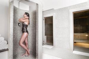 a woman standing in a shower in a bathroom at InterContinental Genève by IHG in Geneva