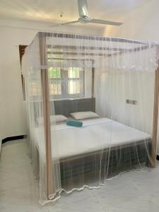 1 cama con dosel en una habitación con ventana en Aldea bleu, en Midigama East