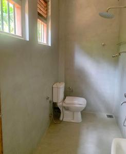 a bathroom with a toilet and a window at Aldea bleu in Midigama