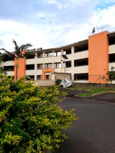 ein orangefarbenes und weißes Gebäude mit einem Parkplatz in der Unterkunft Stay In Tahiti- Bel F3 moderne avec magnifique vue Panoramique sur Papeete in Papeete