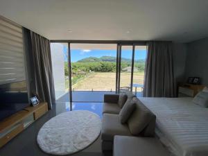 a bedroom with a bed and a couch and a large window at Amazing Pool 3BR Villa @ Chalong in Phuket Town