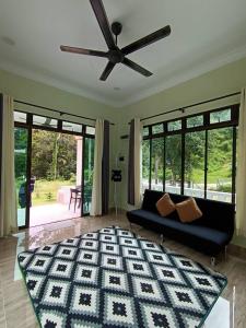 a living room with a couch and a ceiling fan at Dango1881muslim riverstay in Padang Rengas