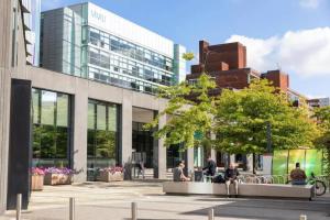 people sitting on benches in front of a building at Morden Apartment in City Centre in Manchester