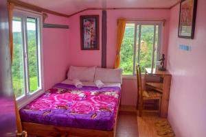 um quarto com uma cama com lençóis cor-de-rosa e rosas em BANAUE EVERGREEN HOSTEL AND RESTAURANT em Banaue