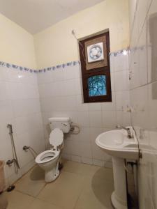 a bathroom with a toilet and a sink with a window at HOTEL THE CORBETT VANSH in Rāmnagar