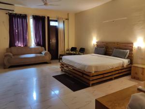 a bedroom with a large bed and a couch at HOTEL THE CORBETT VANSH in Rāmnagar