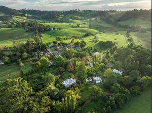 an aerial view of a house in a green field at Velvet Pear Cottage in Central Tilba