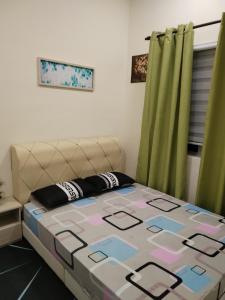 Cama en habitación con cortinas verdes en Lekir baiduri homestay en Sitiawan