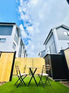 two chairs and a table in front of two buildings at Sunny Oasis- Modern Loft Hidden on Cashel in Christchurch