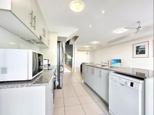 a kitchen with white cabinets and a counter top at Waterfront 'Beachside' Apartment - Ocean View, Central location, Pool, Wifi, King bed, Deluxe Spa Ensuite in Nelly Bay