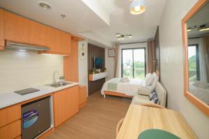 a room with a kitchen and a bed in the background at RcplacePH at Pinesuites Tagaytay in Tagaytay