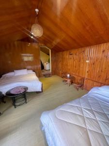 1 dormitorio con 2 camas y pared de madera en The Breeze View Lodge - Tagaytay, en Ulot