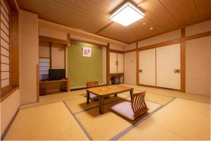 a room with a table and chairs and a television at Suminoyu in Yamanouchi