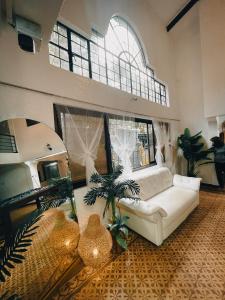 a living room with a white couch and palm trees at Sky Rancho Hostel in Tagaytay