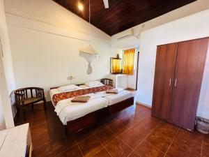 1 dormitorio con 1 cama y armario de madera en Star Holiday Resort, en Hikkaduwa