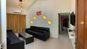 a living room with a black couch and a tv at Calangute apartment in Calangute