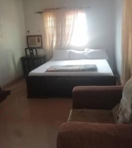 a bedroom with a bed with a window and a couch at Diamond Hotel close to Intl Airport, omole ikeja in Mawere