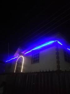 dom z niebieskimi światłami na dachu w nocy w obiekcie Diamond Hotel close to Intl Airport, omole ikeja w mieście Mawere
