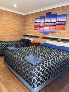 a bedroom with a large bed and a brick wall at Coonamble Motel in Coonamble