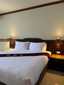 una camera da letto con un grande letto con lenzuola e cuscini bianchi di Suntara Wellness Resort & Hotel a Chachoengsao