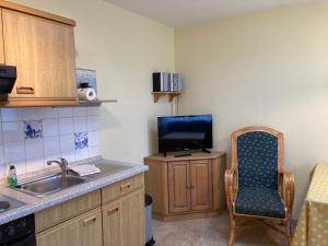 a kitchen with a sink and a tv and a chair at Nordsee 402 in Wangerooge