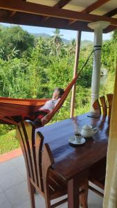 a man sleeping in a hammock at a table at Rainforest River Edge in Deniyaya